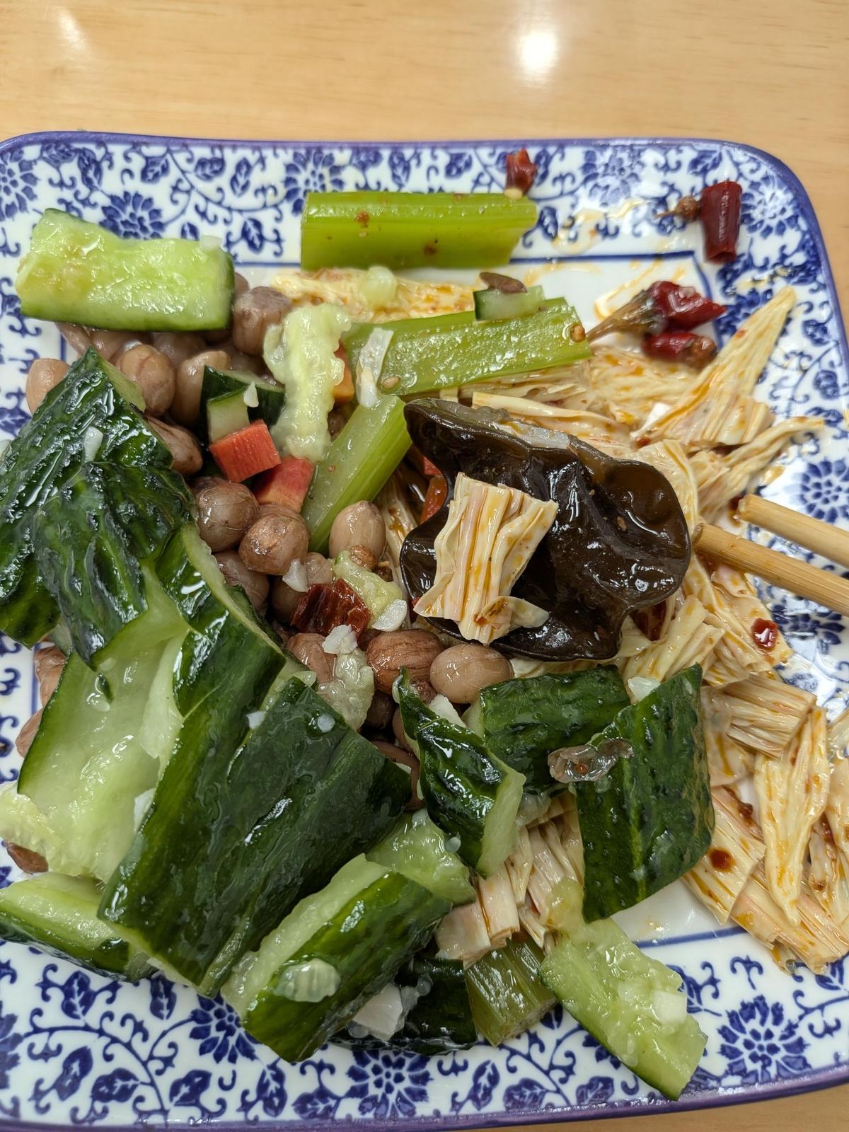 Salade de concombre concassé, céleri, champignons de bois et pois chiches frites, sauce pimentée et ail, baguettes sur plat bleu et blanc