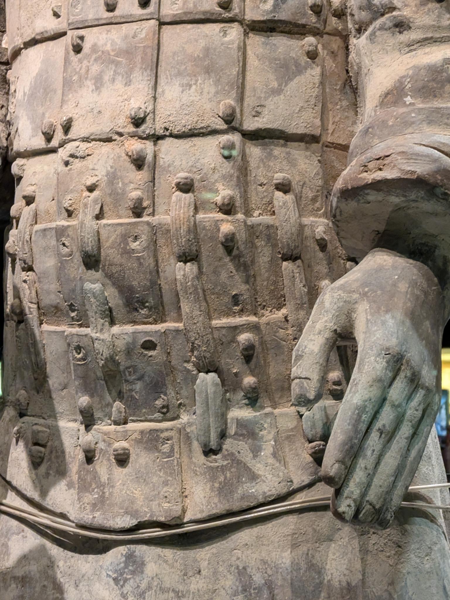 Torse et bras d'une statue, armure à écailles et patine, main sur la hanche