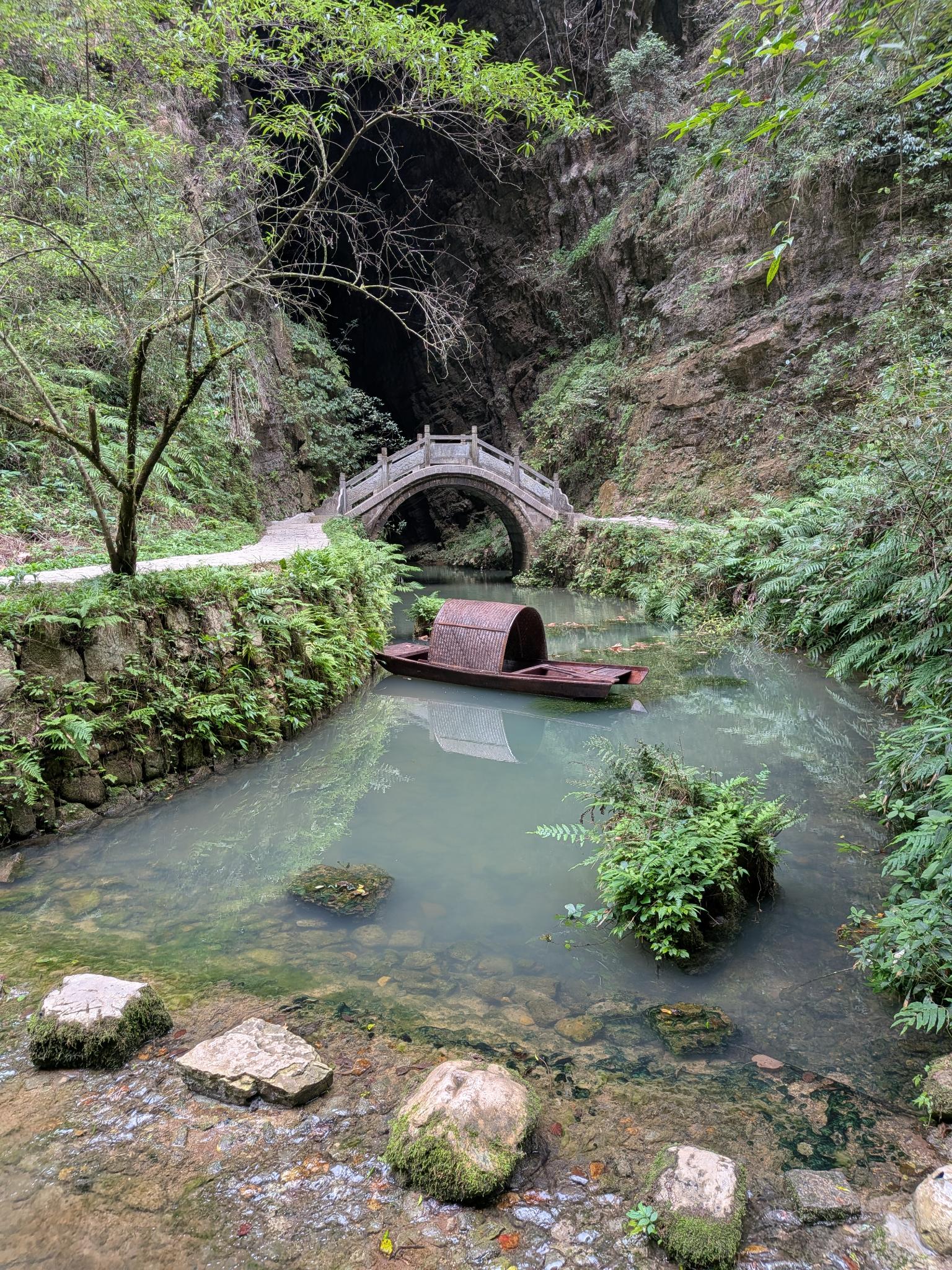 La barque à toit de tuiles et le pont de pierre devant la grotte