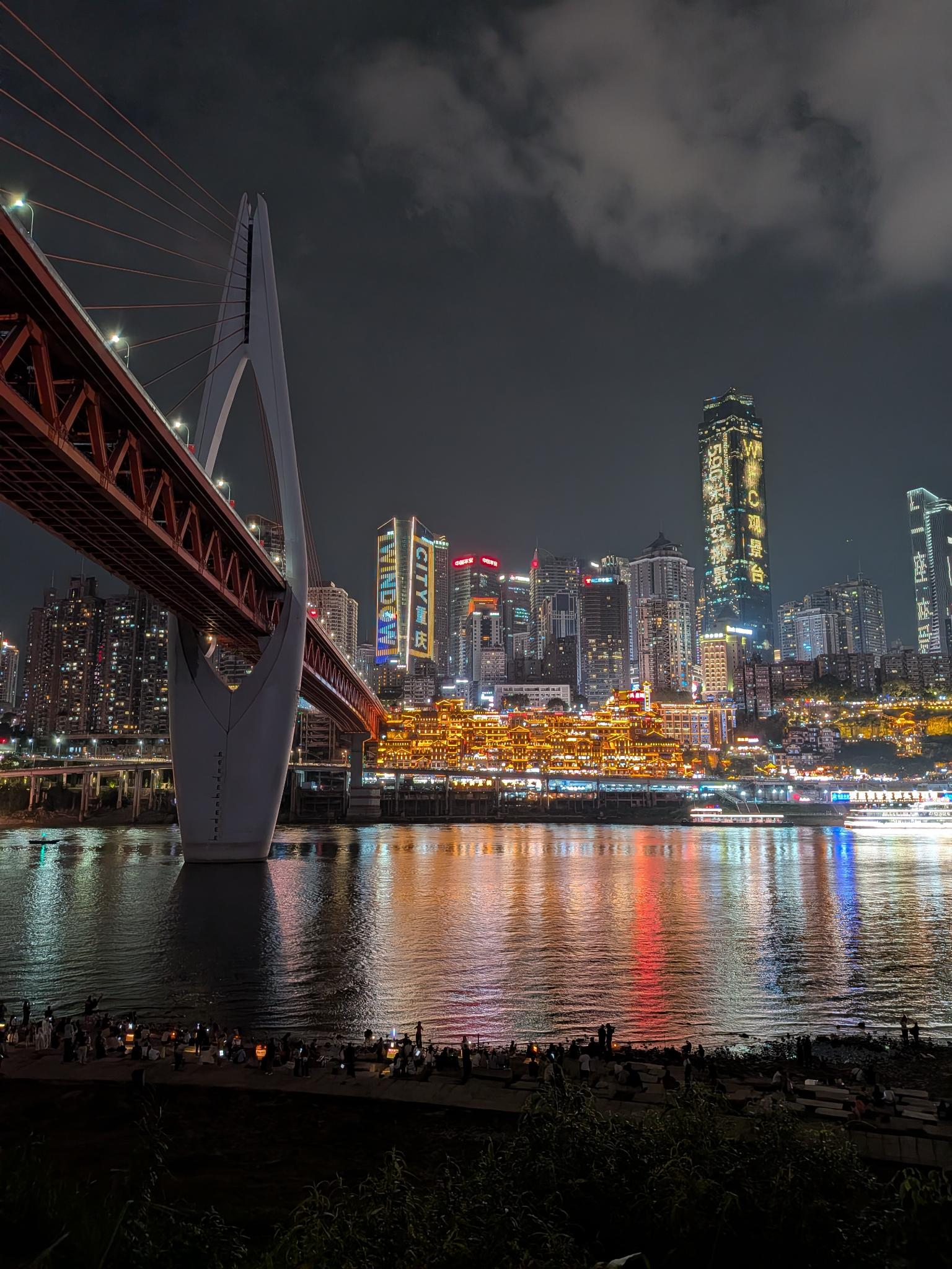 Hongyadong illuminé de l'autre rive, le pont rouge au premier plan
