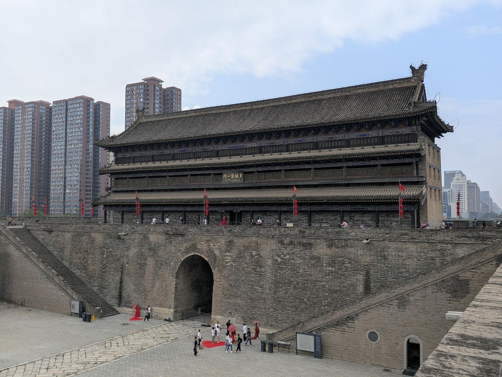 Vue de la porte Nord depuis le sommet du rempart, plaque 古城第一门, hanfu rouges et immeubles modernes derrière le mur