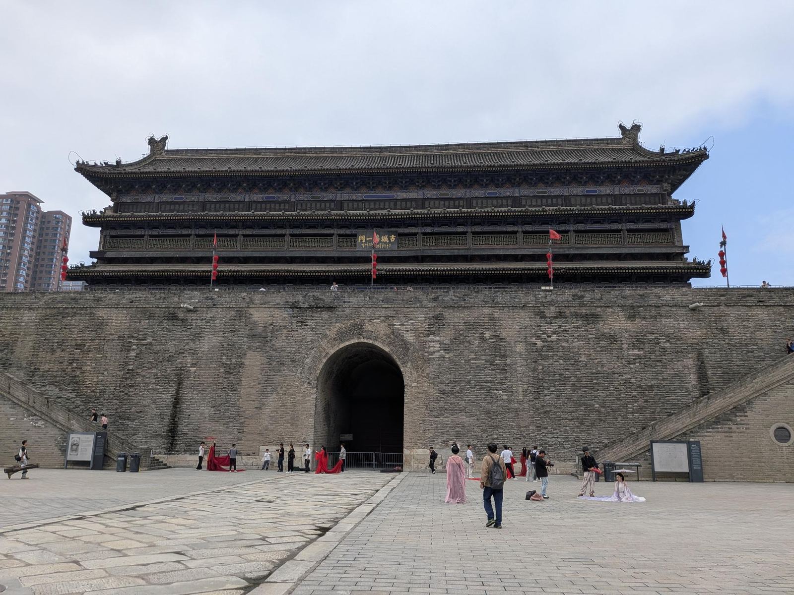 La porte Nord (Anyuanmen) avec sa plaque 古城第一门, son arche tunnel, lanternes et drapeaux rouges, touristes en hanfu sur la place