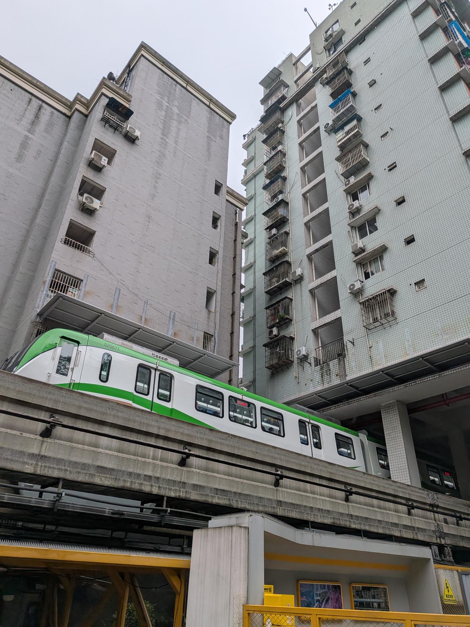 Un monorail vert et blanc sur son viaduc, les tours d'habitation en toile de fond