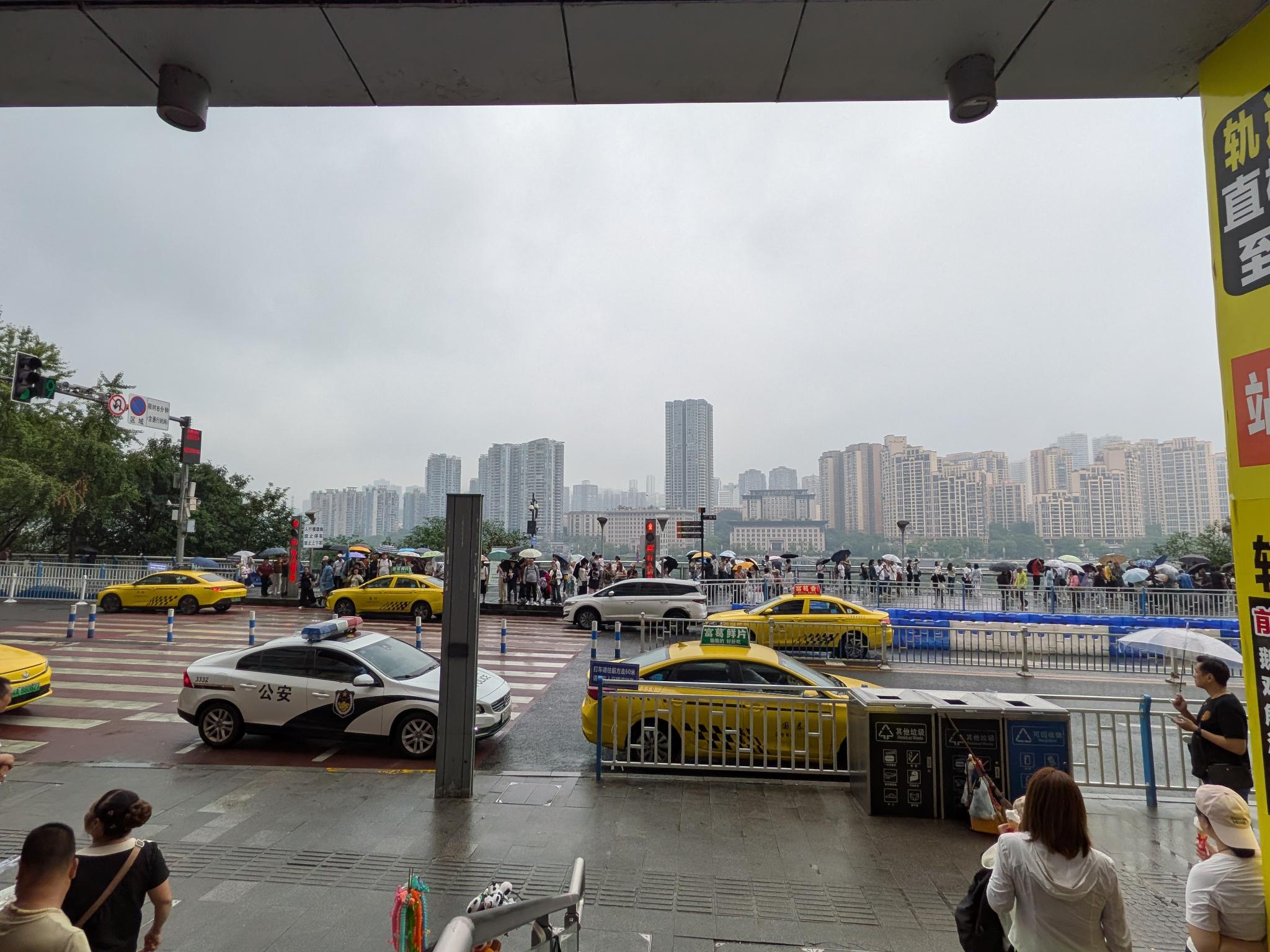 La place de la station, les taxis jaunes et la pluie