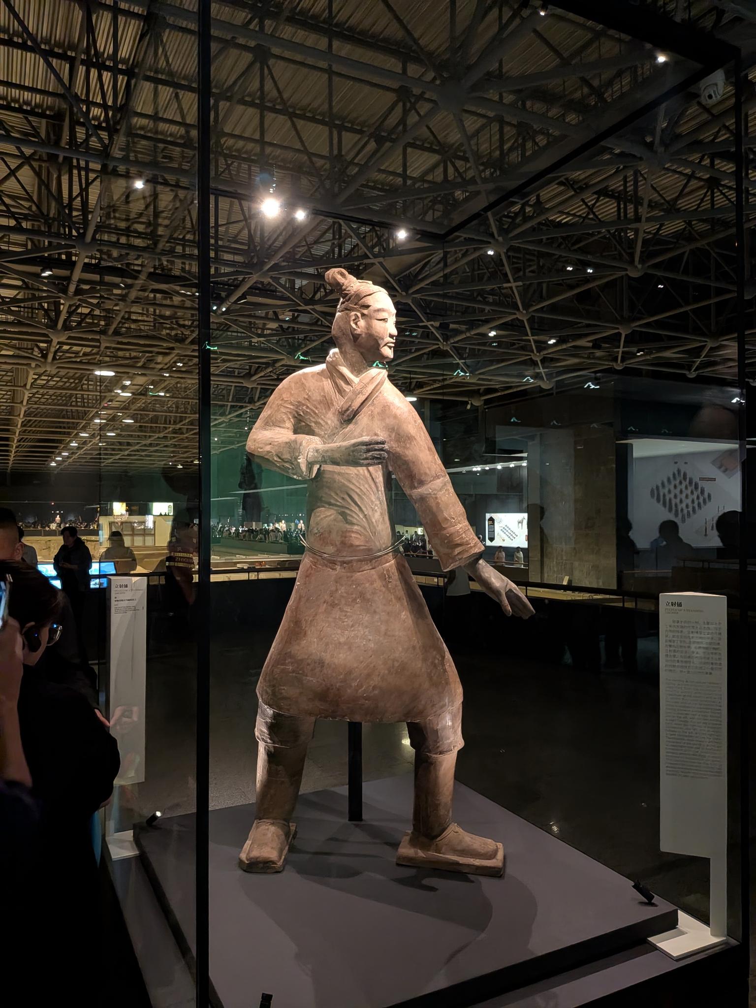 L'archer debout (立射俑) derrière sa vitrine, bras tendu et tige de support