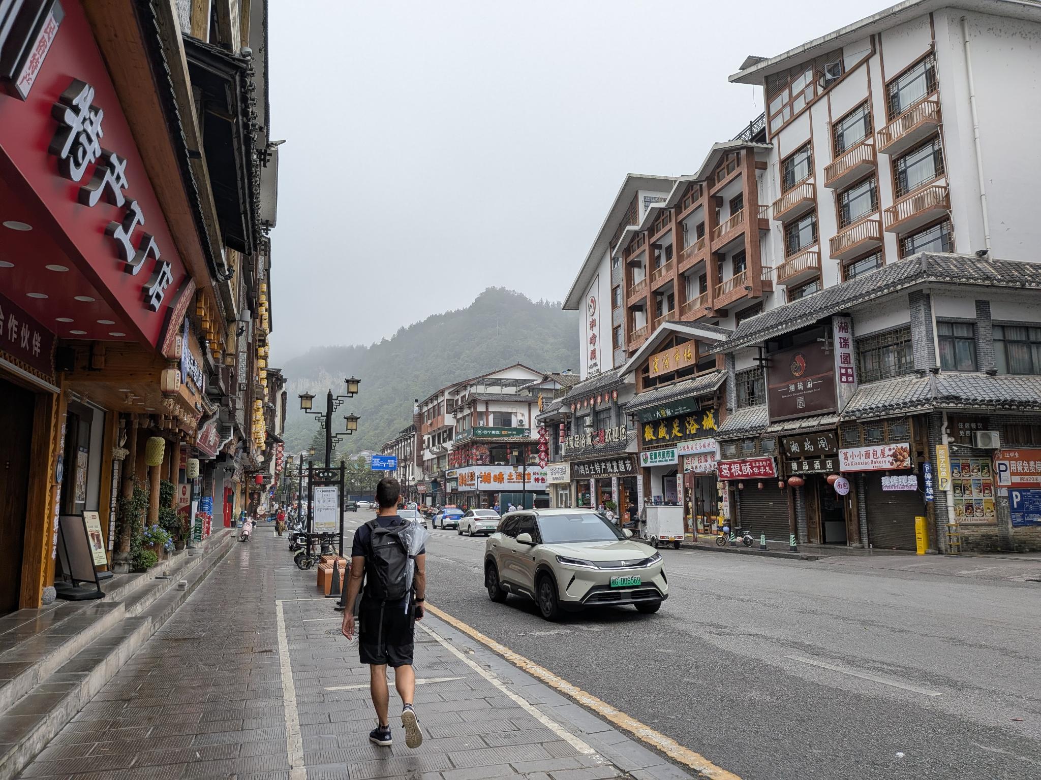 La rue pluvieuse de la ville du canyon, ses boutiques de 特产 et ses panneaux 足浴