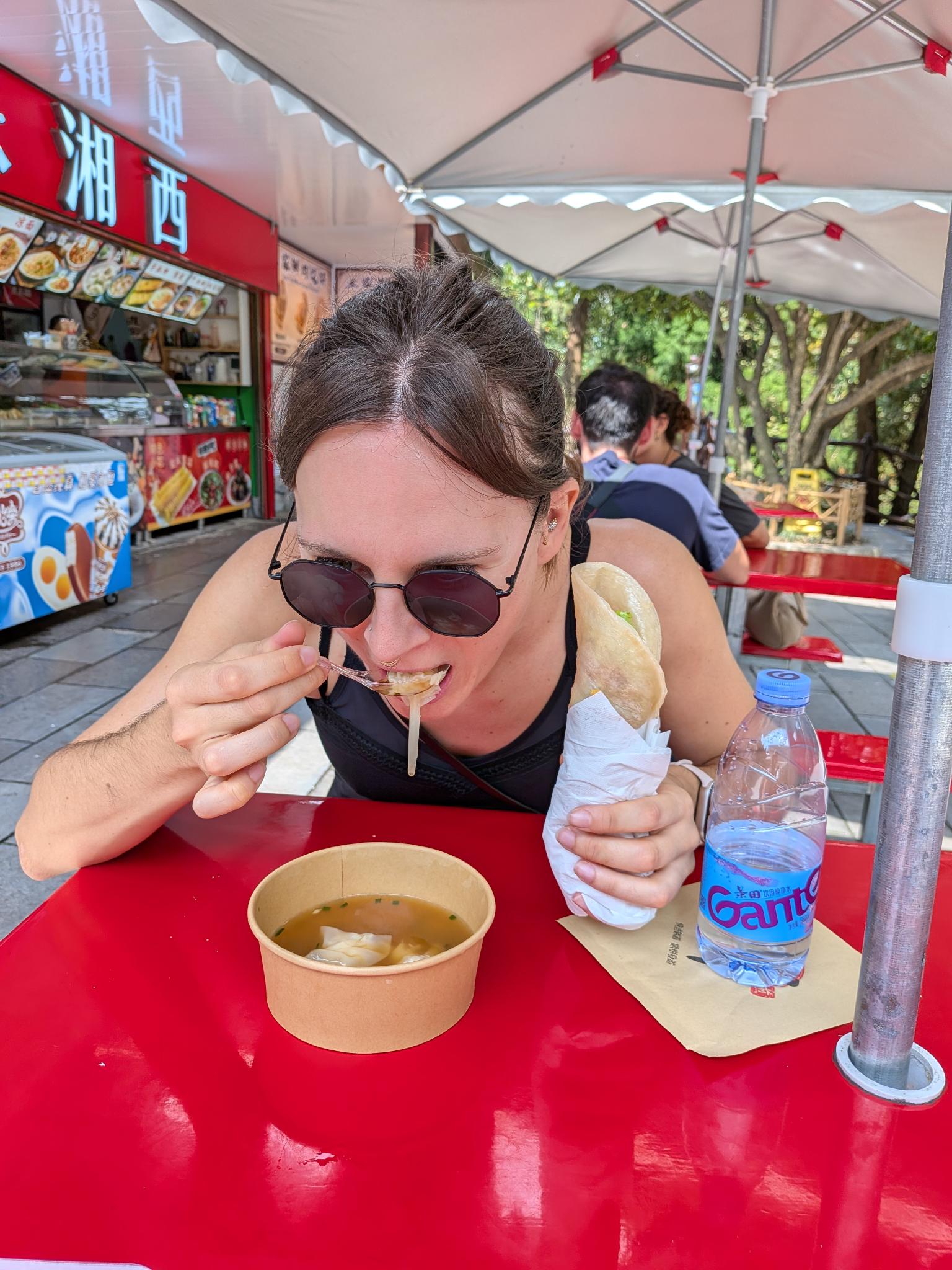 Marion avec ses bols de wonton sous le parasol rouge, street food de fin de journée