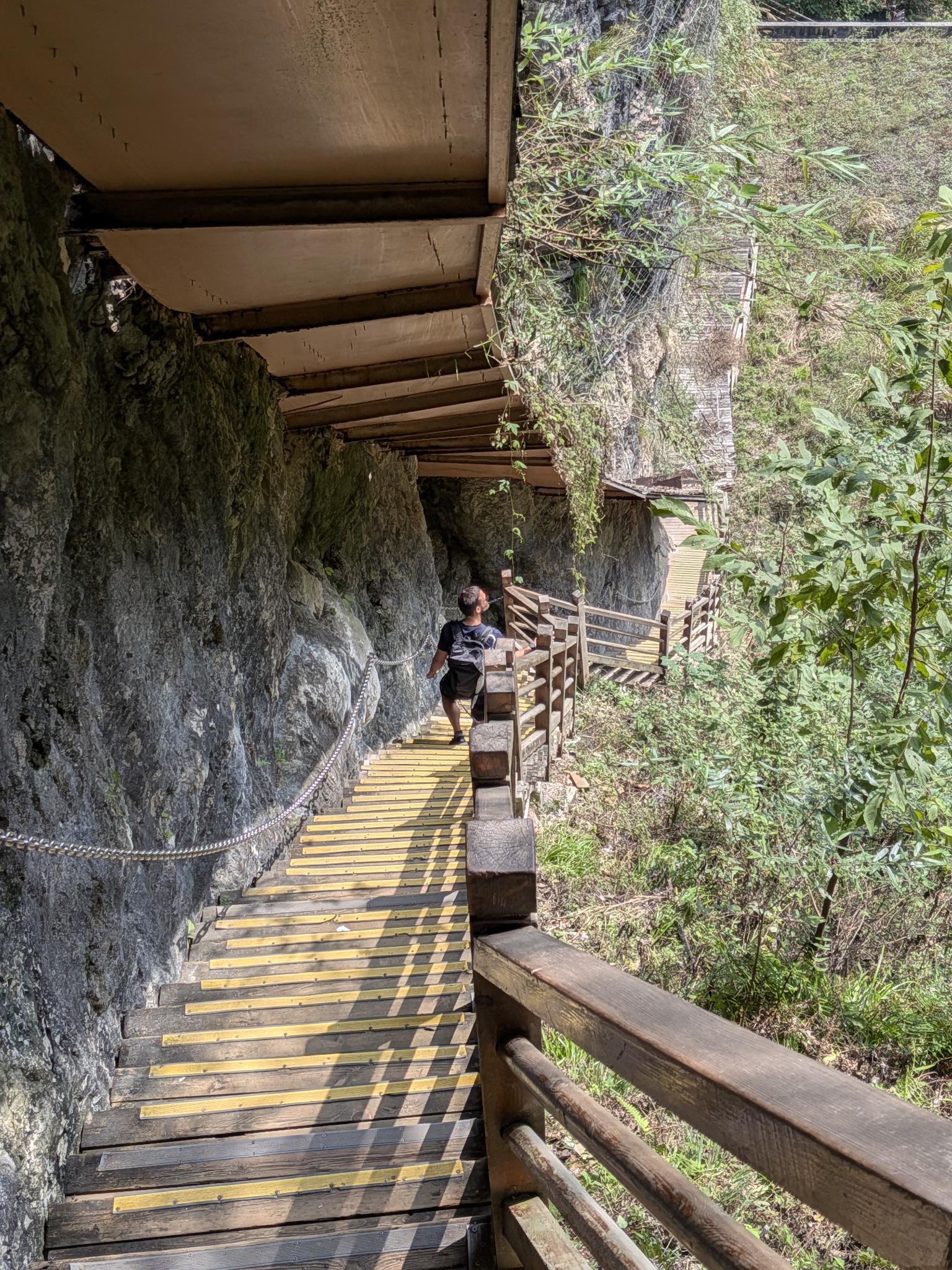 L'escalier de planches au pied de la roche grise, son passage couvert dans le roc