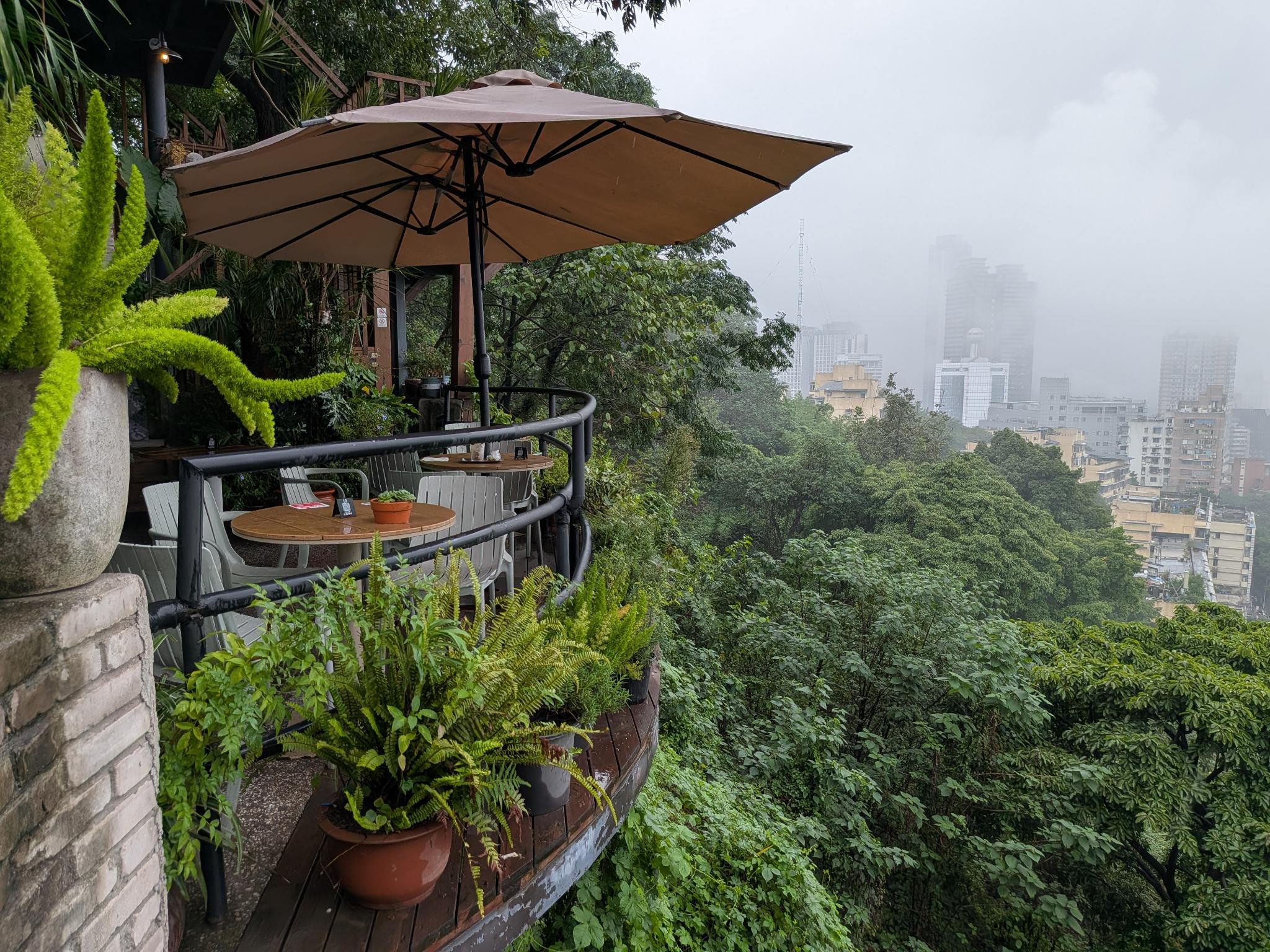 La terrasse de café au milieu des arbres, la ville en contrebas