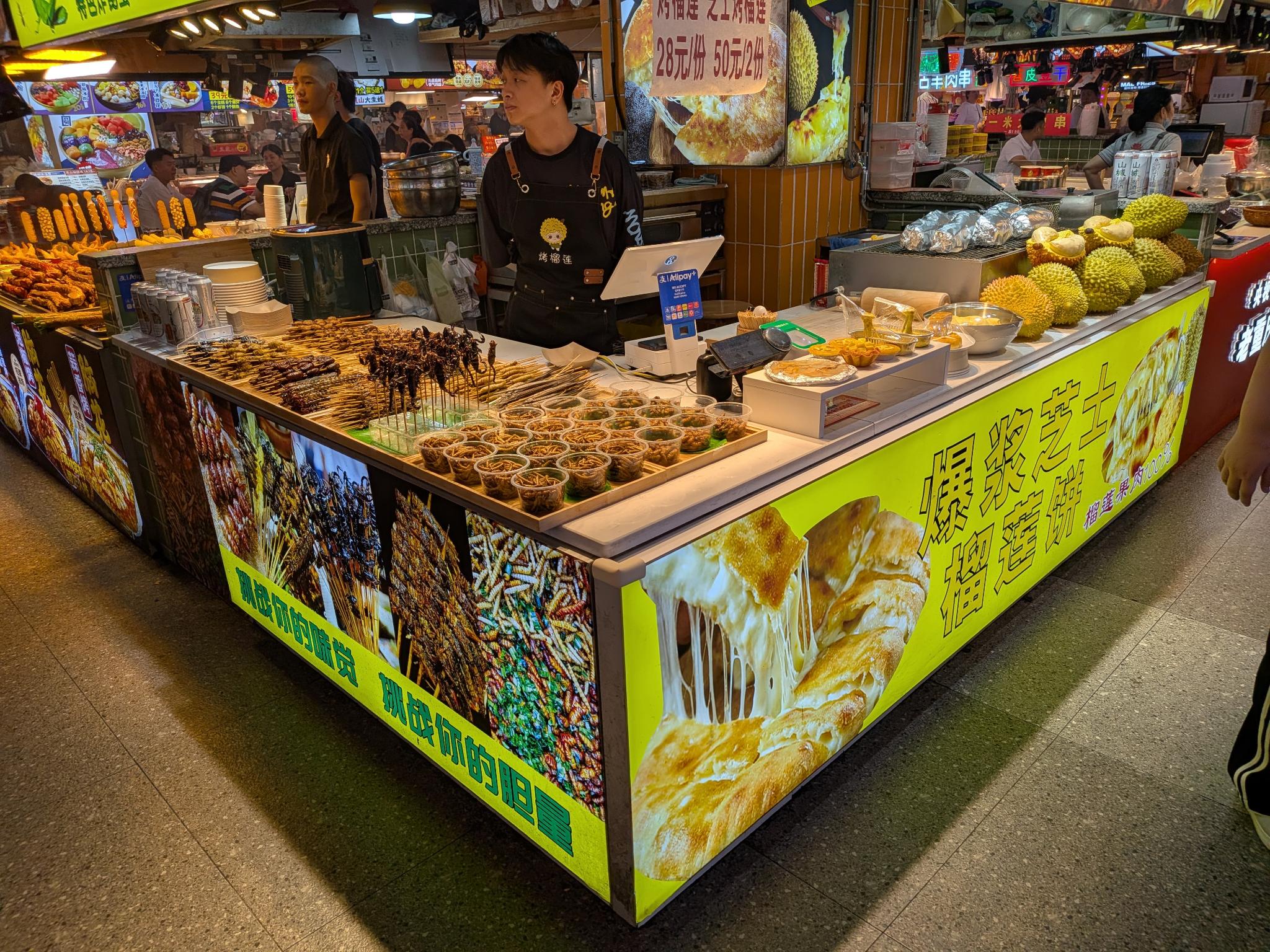 Un stand de gâteaux au durian, avec les durians entiers exposés