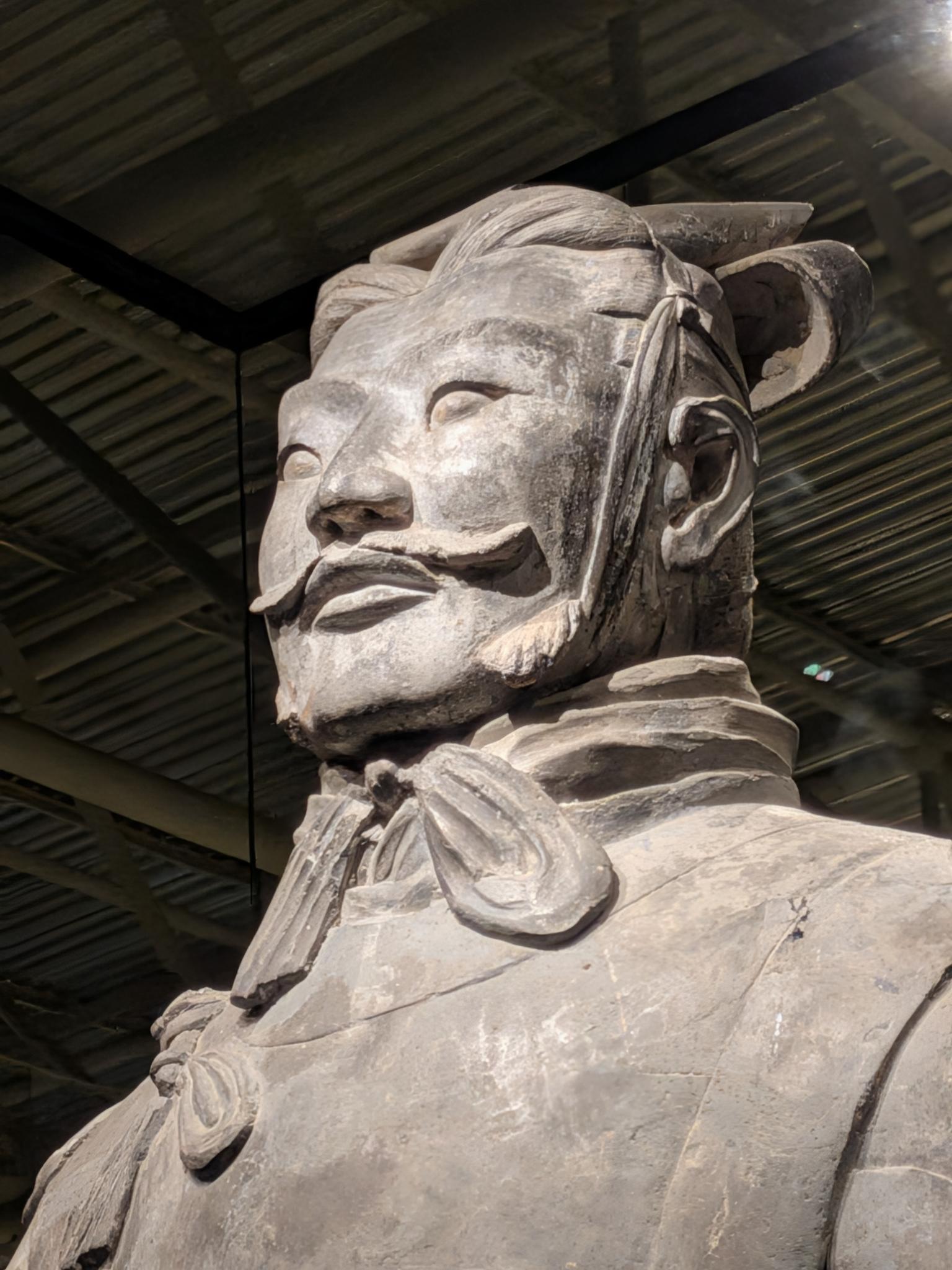 Tête et épaules d'un guerrier sous le toit ondulado de la salle d'exposition