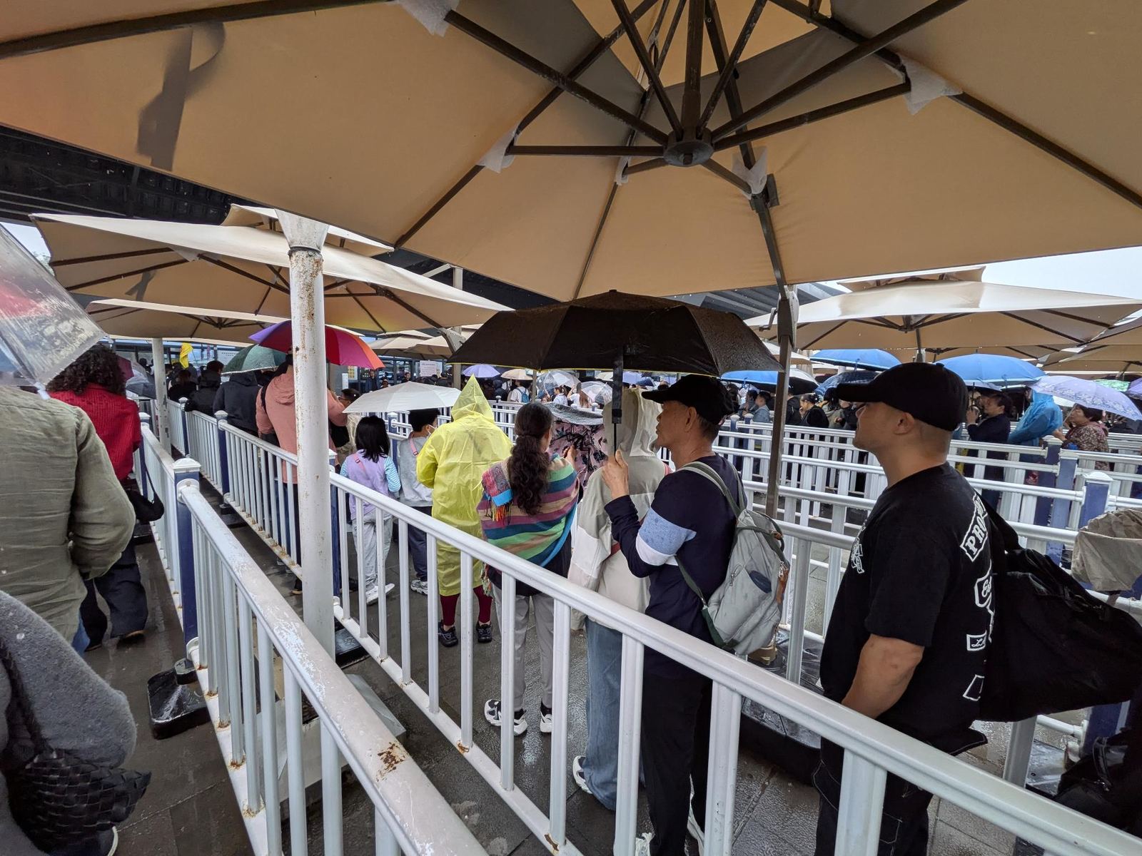 File d'attente de visiteurs sous les parapluies et les ombrelles de la gare d'entrée, sous la pluie
