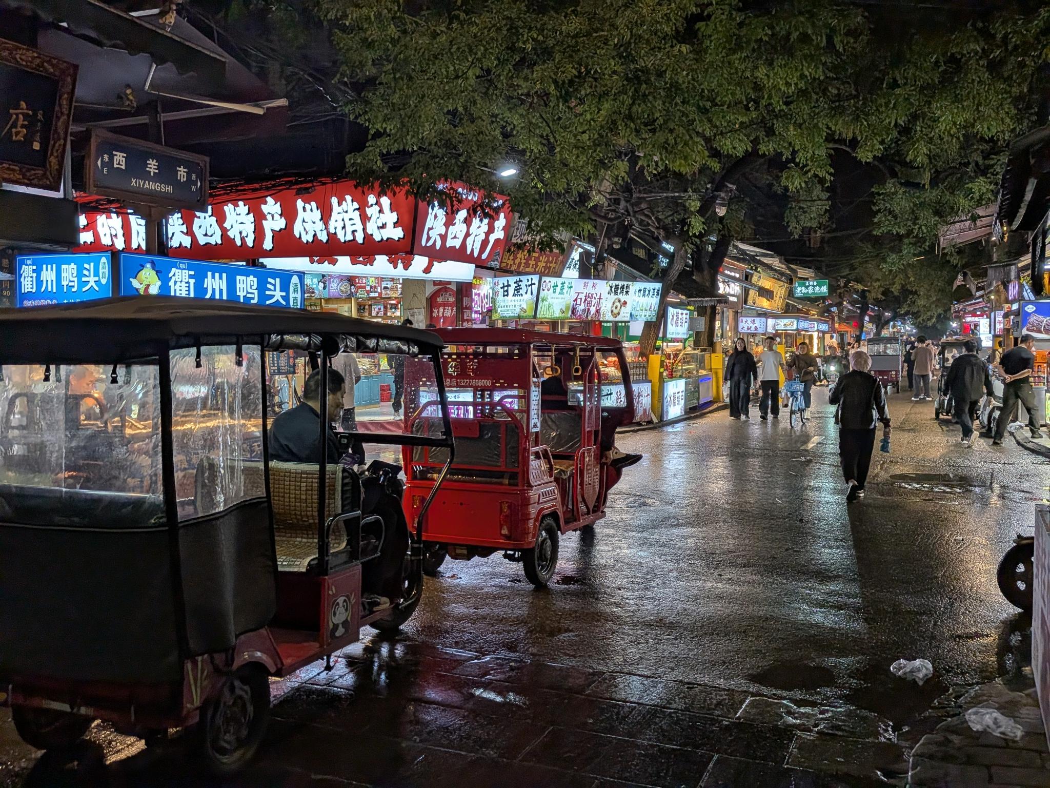 Rue West Yangshi la nuit, enseigne 西羊市, tricycles électriques rouges et échoppes de nourriture lumineuses