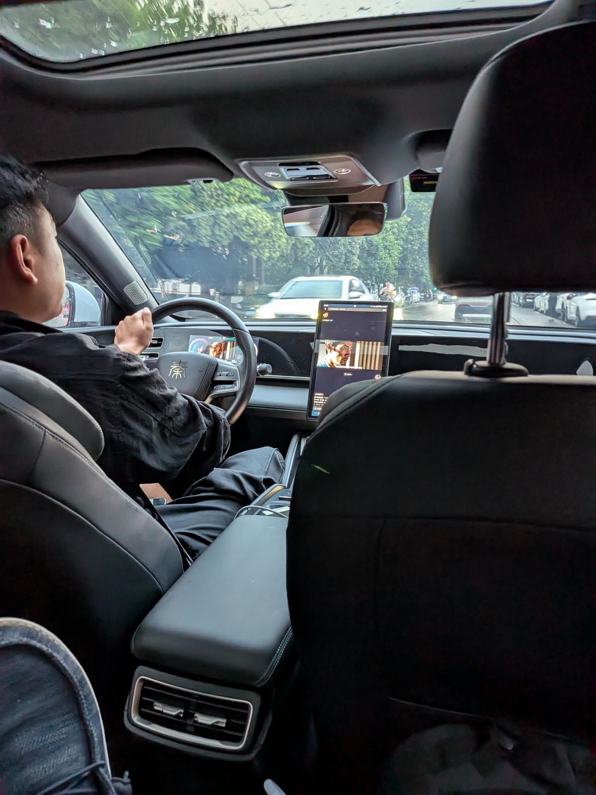 Le volant d'une voiture BYD avec le caractère 秦 (Qin), pluie sur le pare-brise