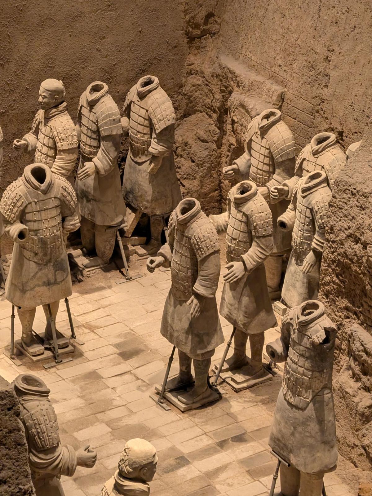 Groupe de guerriers, la plupart sans tête, armure à écailles, tiges métalliques au pied