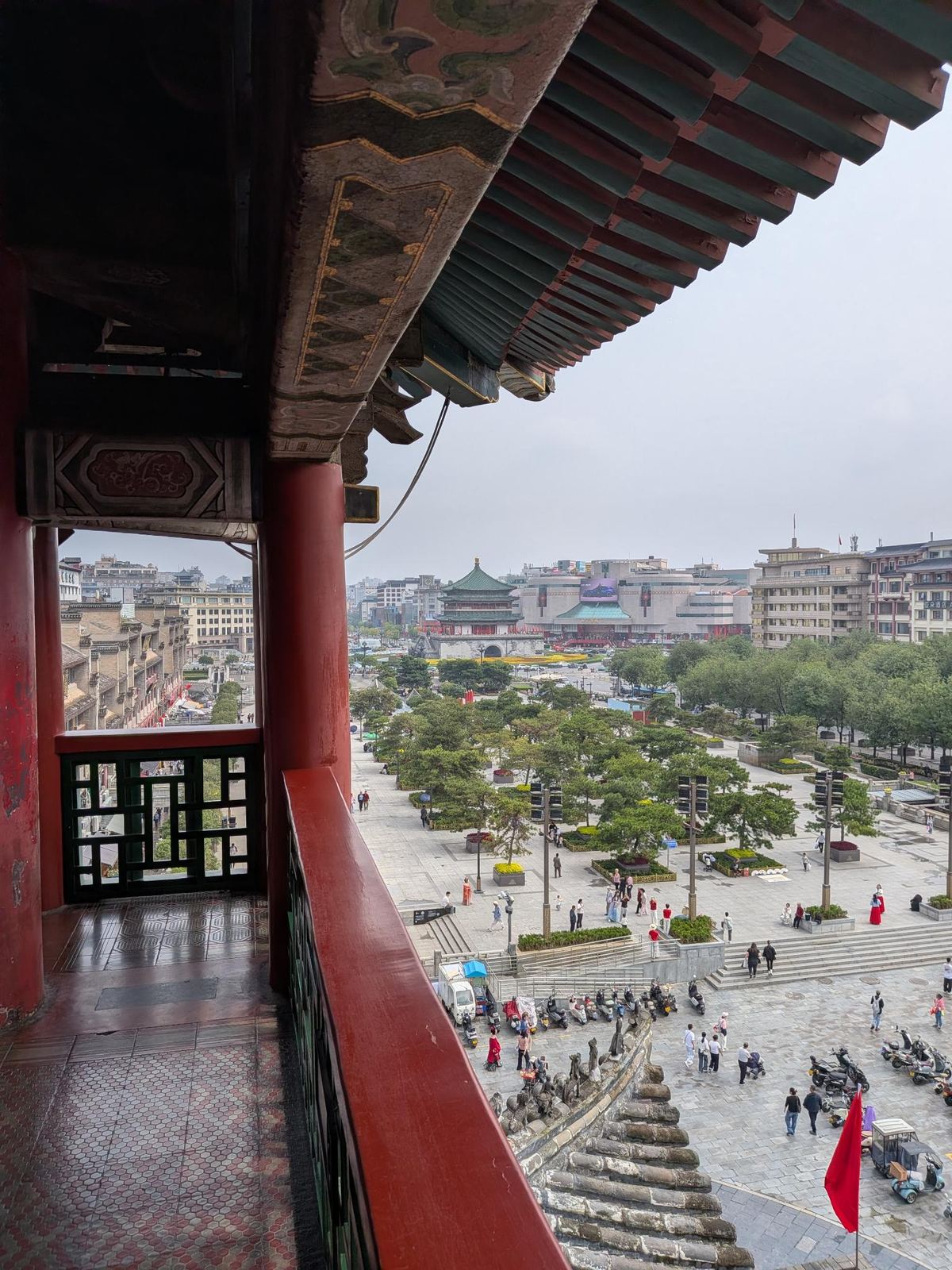 Vue depuis l'étage de la tour, encorbellement peint, balcon rouge, place pavée en contrebas