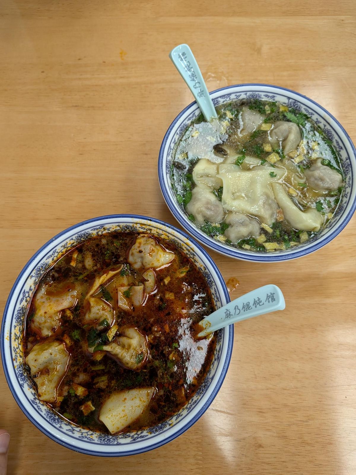 Deux bols de wonton : bouillon clair et bouillon au piment, cuillères bleues 麻乃馄饨馆