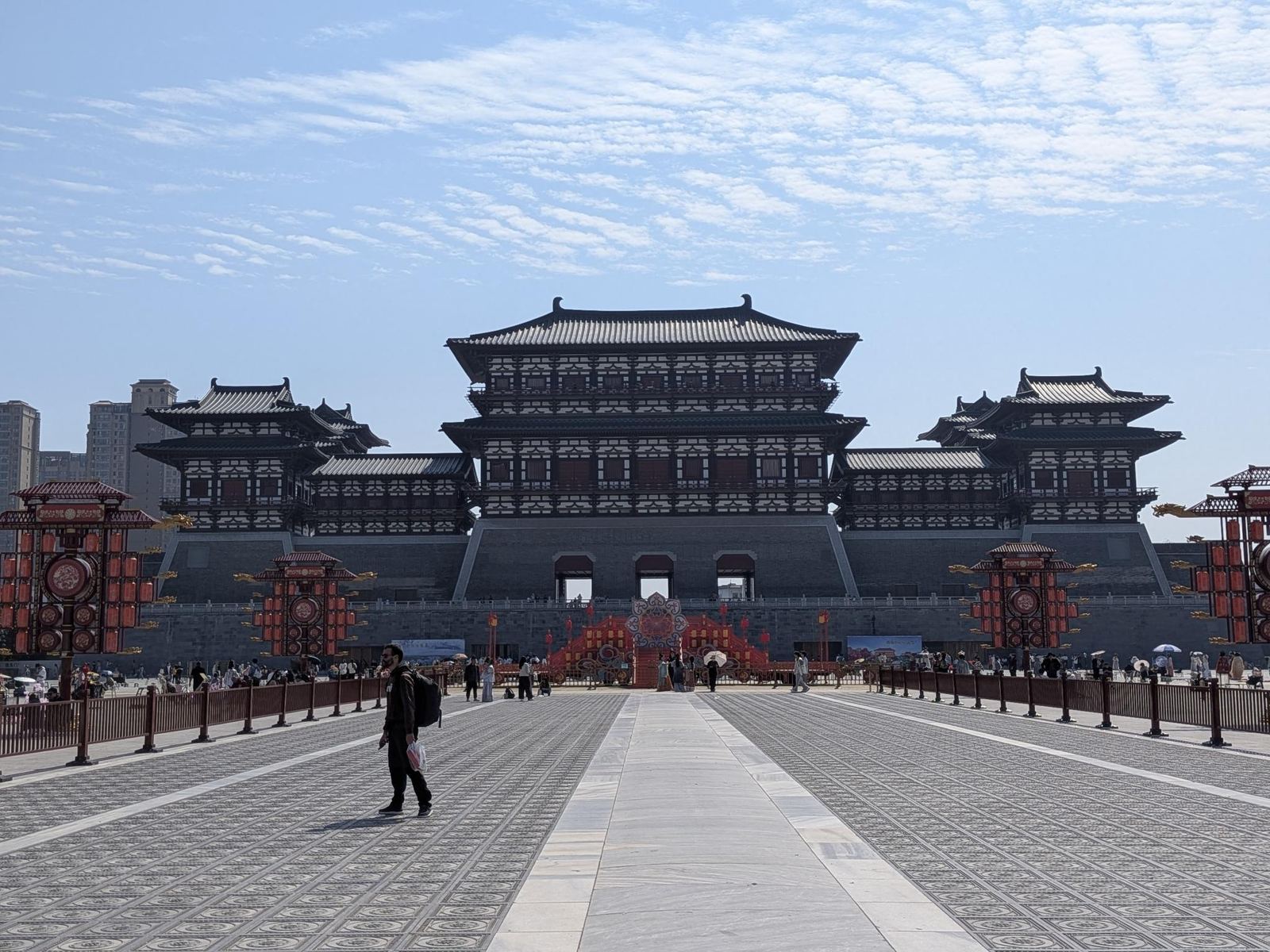 La grande porte Yingtianmen reconstruite, pavillon central à toits multiples sur sa plateforme de briques aux trois arches, tours d'angle et courtines, place pavée aux lanternes et tambours, immeubles modernes au loin