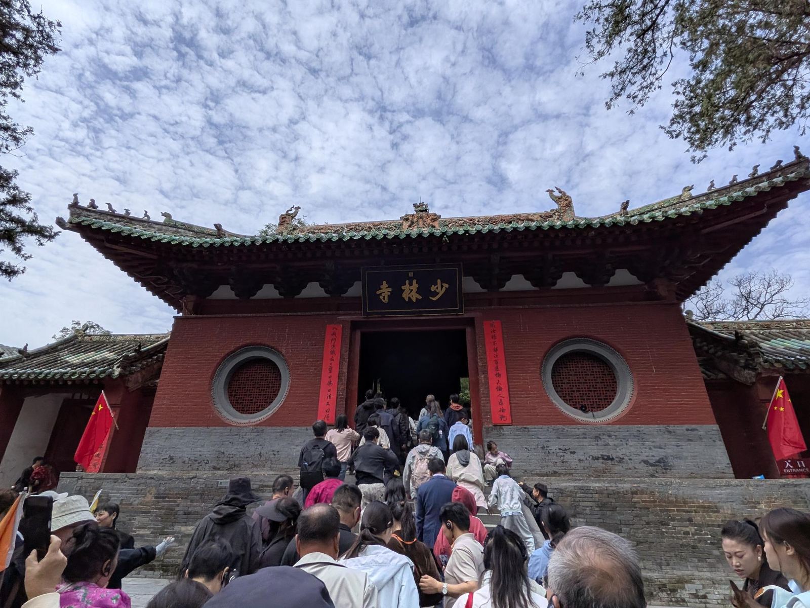 La grande porte du temple de Shaolin, plaque 少林寺, foule de touristes sur les marches, drapeaux chinois de part et d'autre