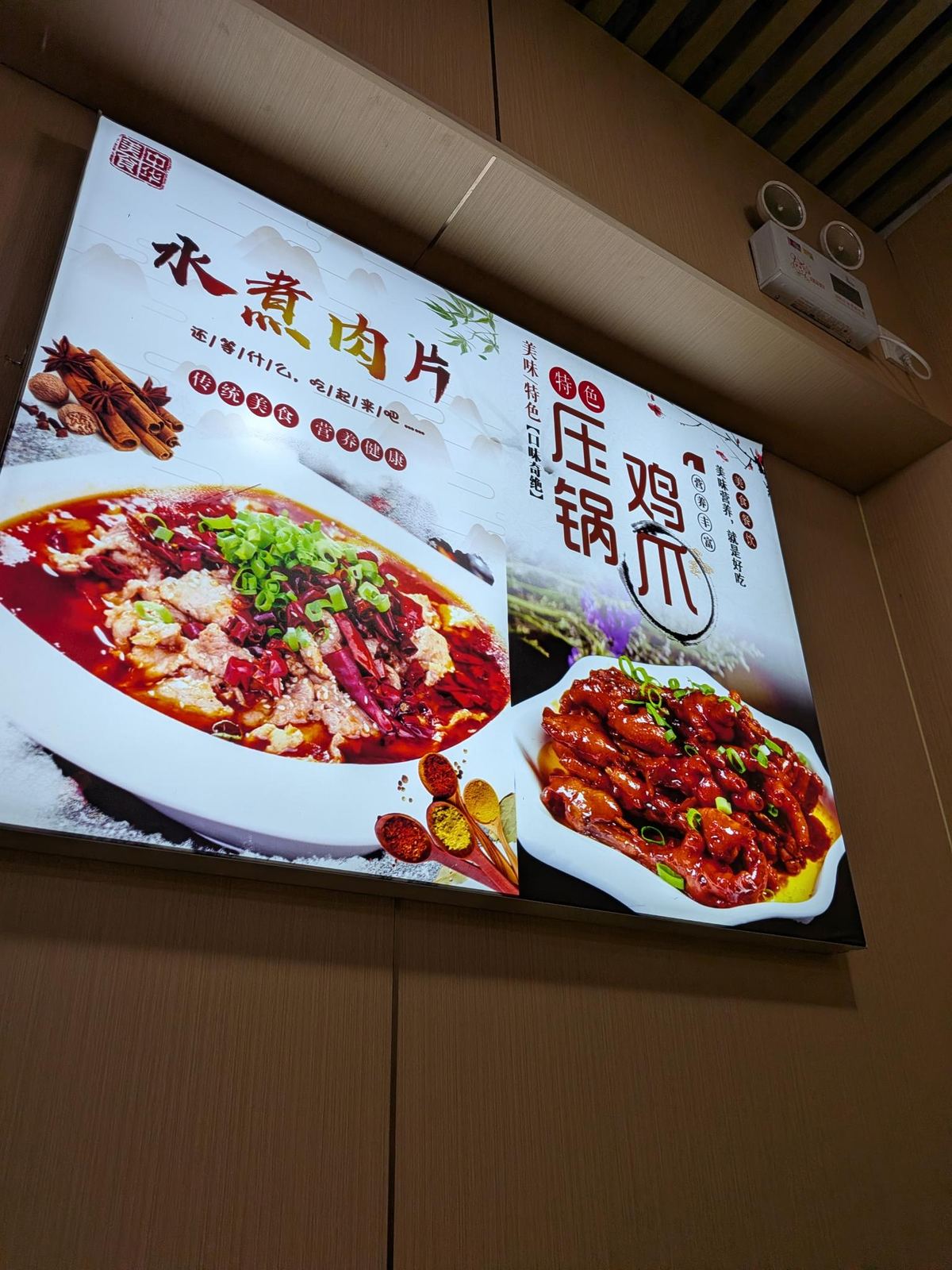 Menu illuminé du resto : photo du 水煮肉片 (tranches de porc dans l'huile de piment) et du 压锅鸡爪 (pattes de poulet braisées), slogans 传统美食 营养健康 et 美味营养 就是好吃